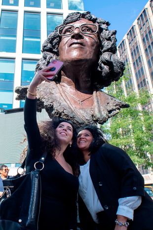 picture of women smiling next to a statue