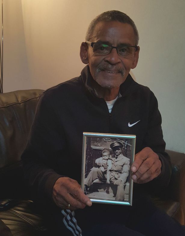 Neville Shenbanjo holding a photo of his father holding him as a baby
