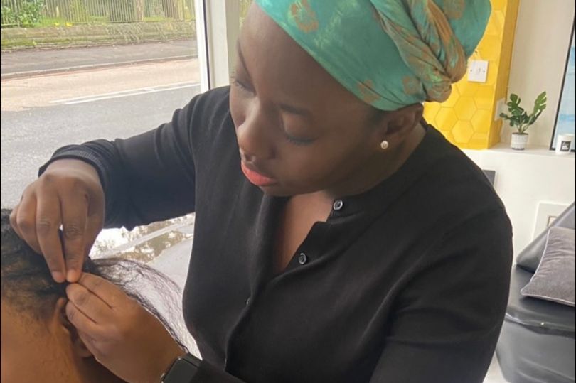 Black woman plaiting a black girls hair