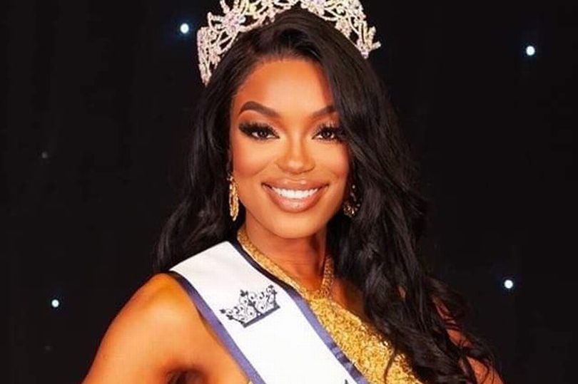 Picture of a black girl smiling with a tiara and a sash around her shoulder
